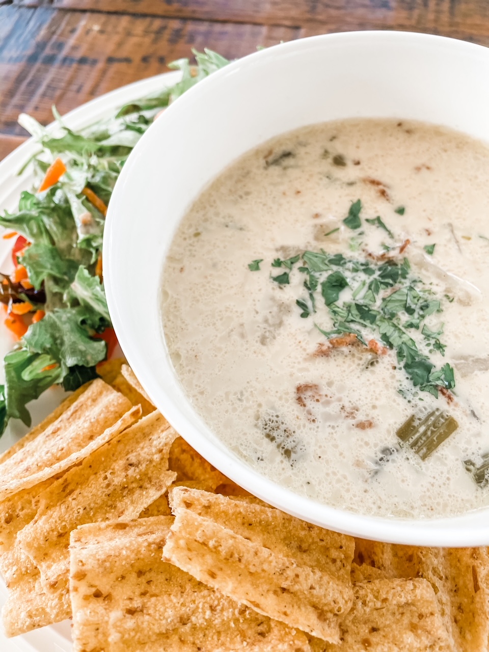 A close-up of the Quick and Creamy Seafood Chowder, accompanied by salad and crackers