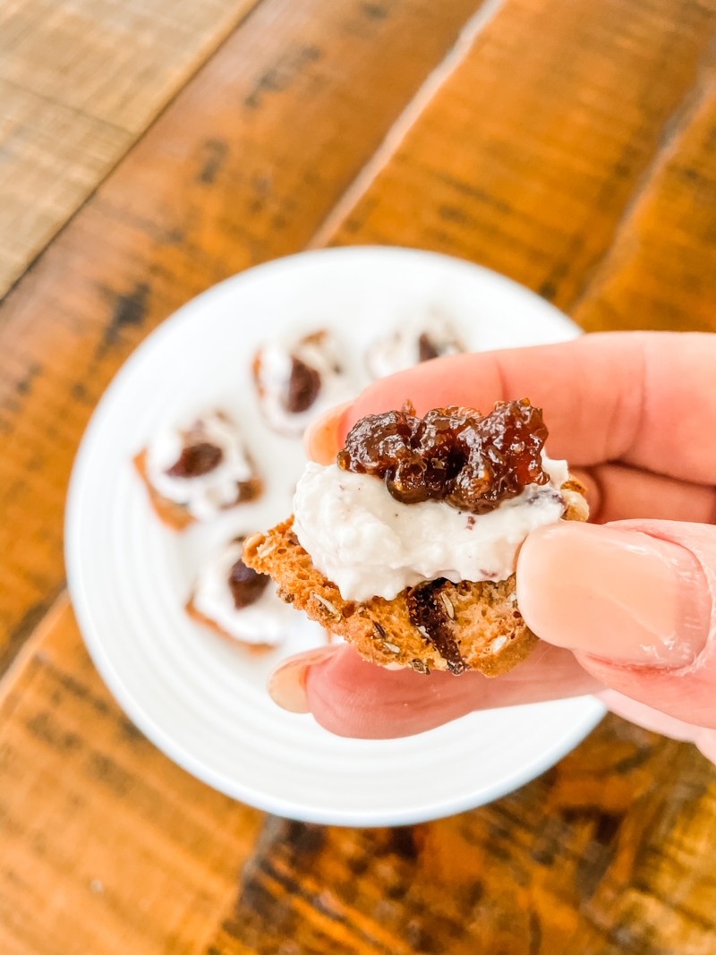 A hand holding one of the Whipped Feta Appetizers with Fig