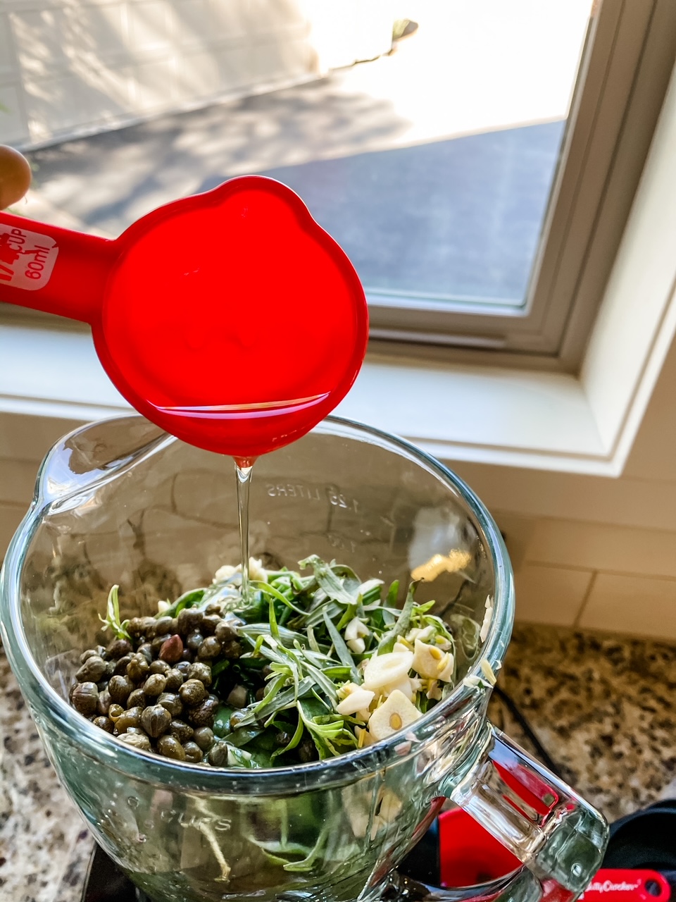 Olive oil being poured in to a blender full of ingredients