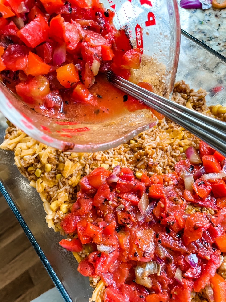 Diced tomatoes being poured into a baking dish