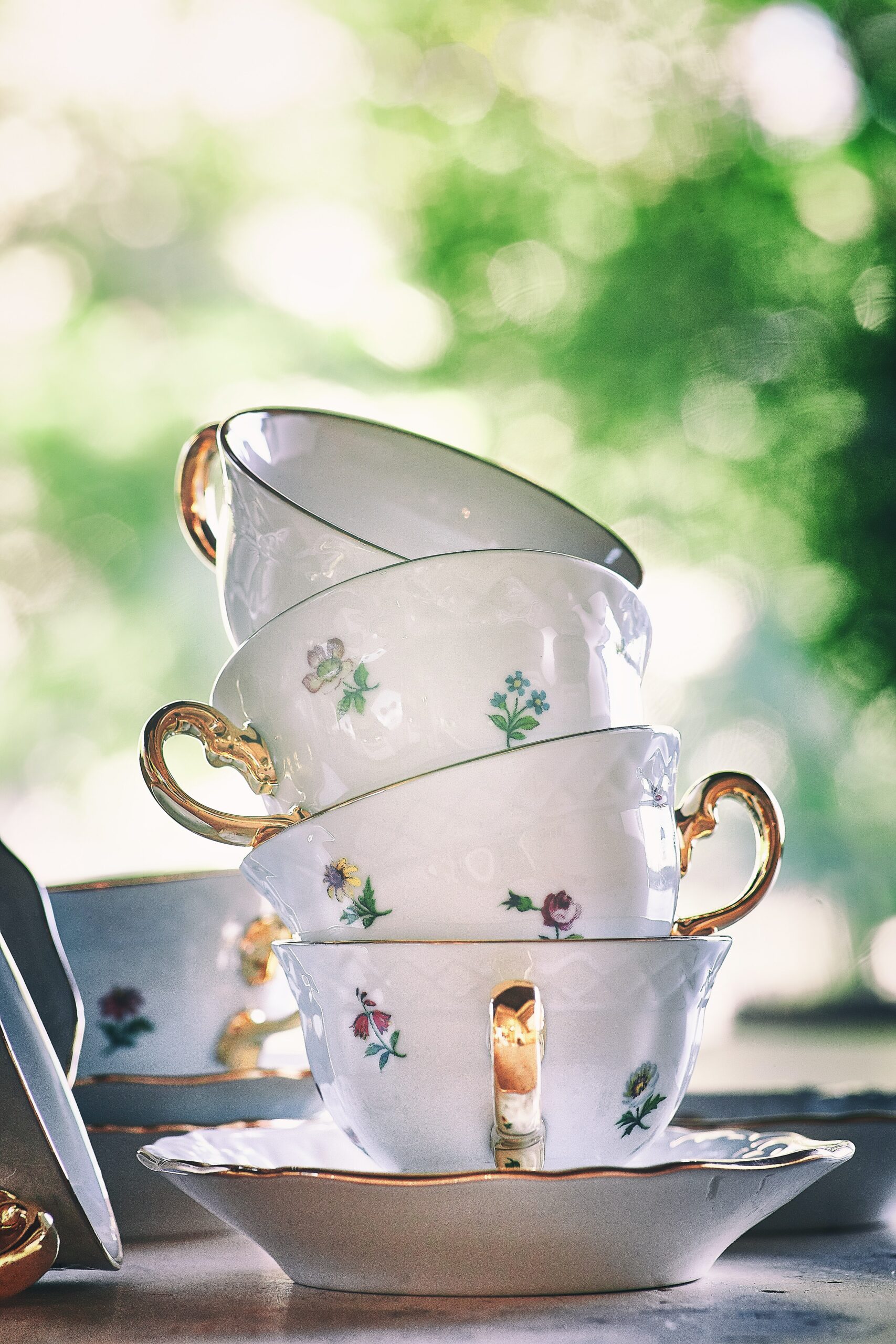 A stack of teacups in front of some foliage. Curating collections is one of Marie's 10 Downsizing Tips and Truths