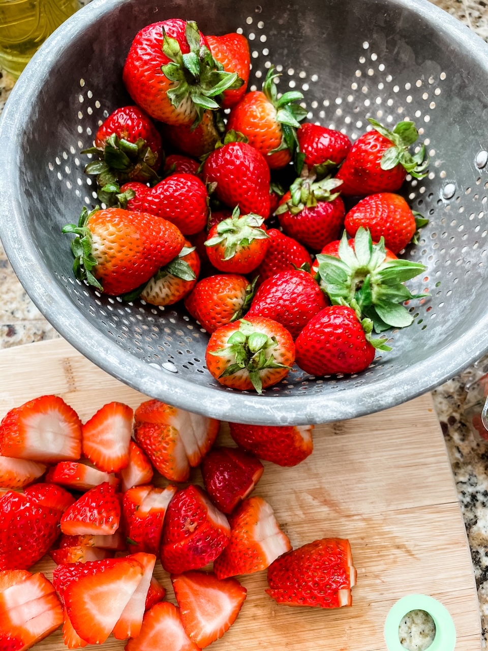 Fresh strawberries, both sliced and in a colander