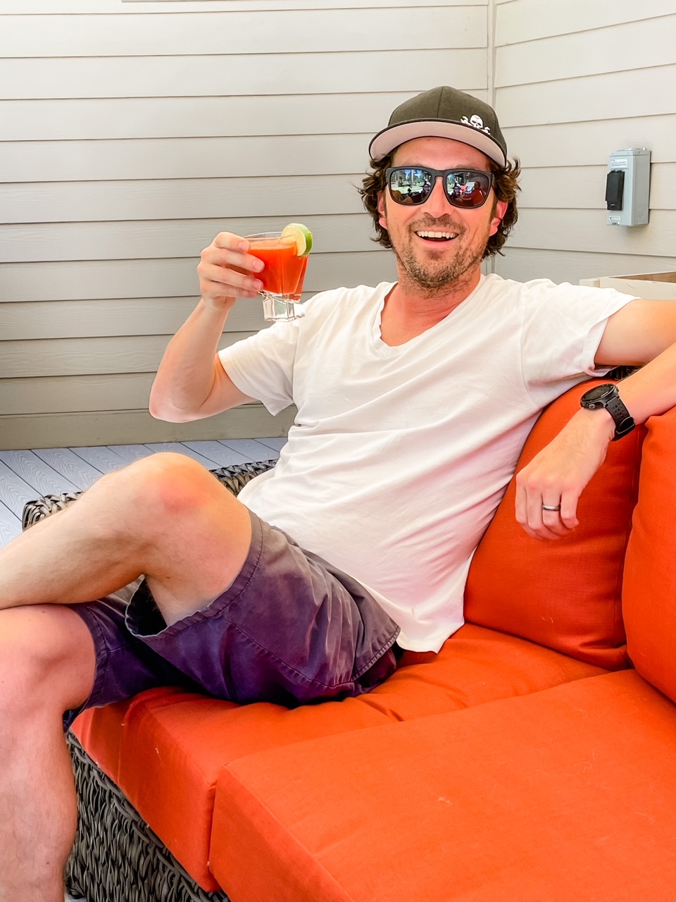 A man holding a Fresh Strawberry Margaritas and sitting on a couch
