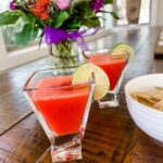 Two cups of the finished Fresh Strawberry Margaritas on a table