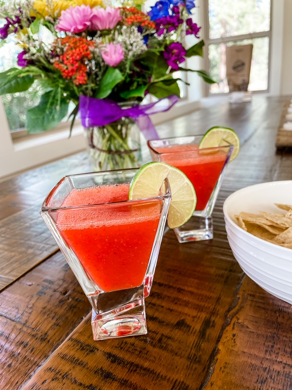 Two cups of the finished Fresh Strawberry Margaritas on a table