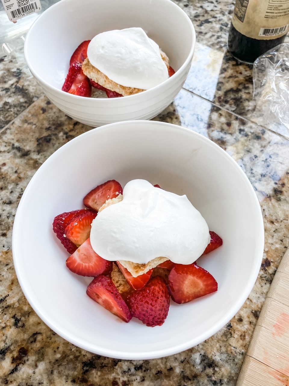 The finished Homemade Shortcake Biscuits topped with strawberries, whipped cream, served in white bowls