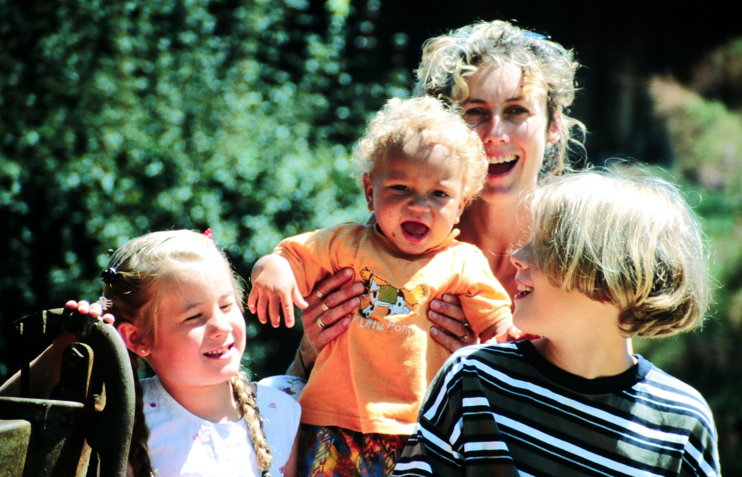 A woman with two children and holding up a baby