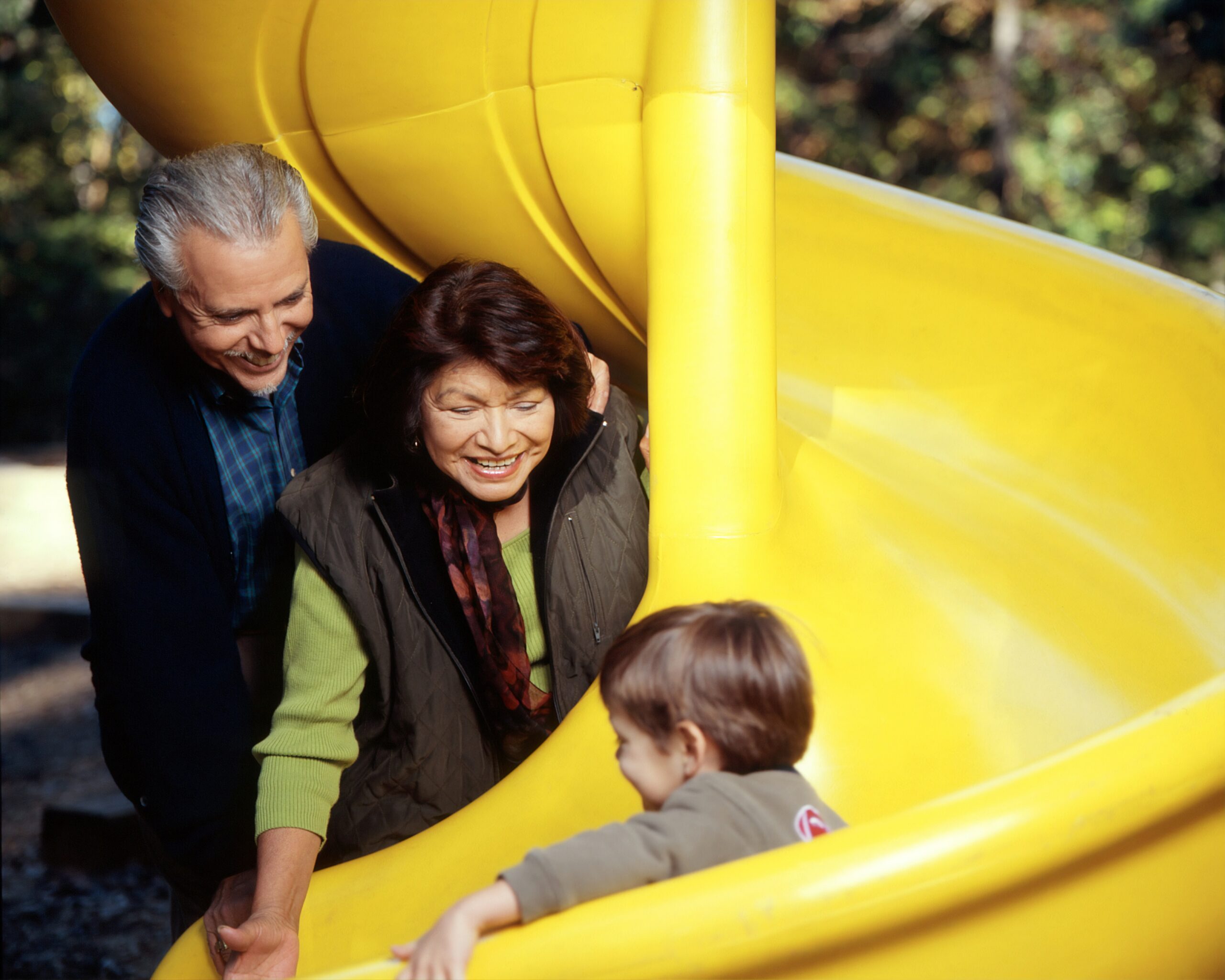 Grandparents wathing their grandchild go down a slide