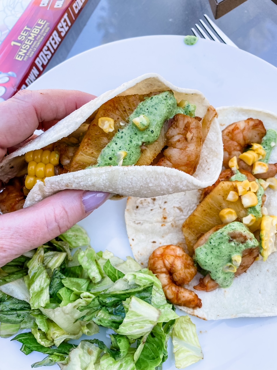 A hand picking up one of the shrimp street tacos