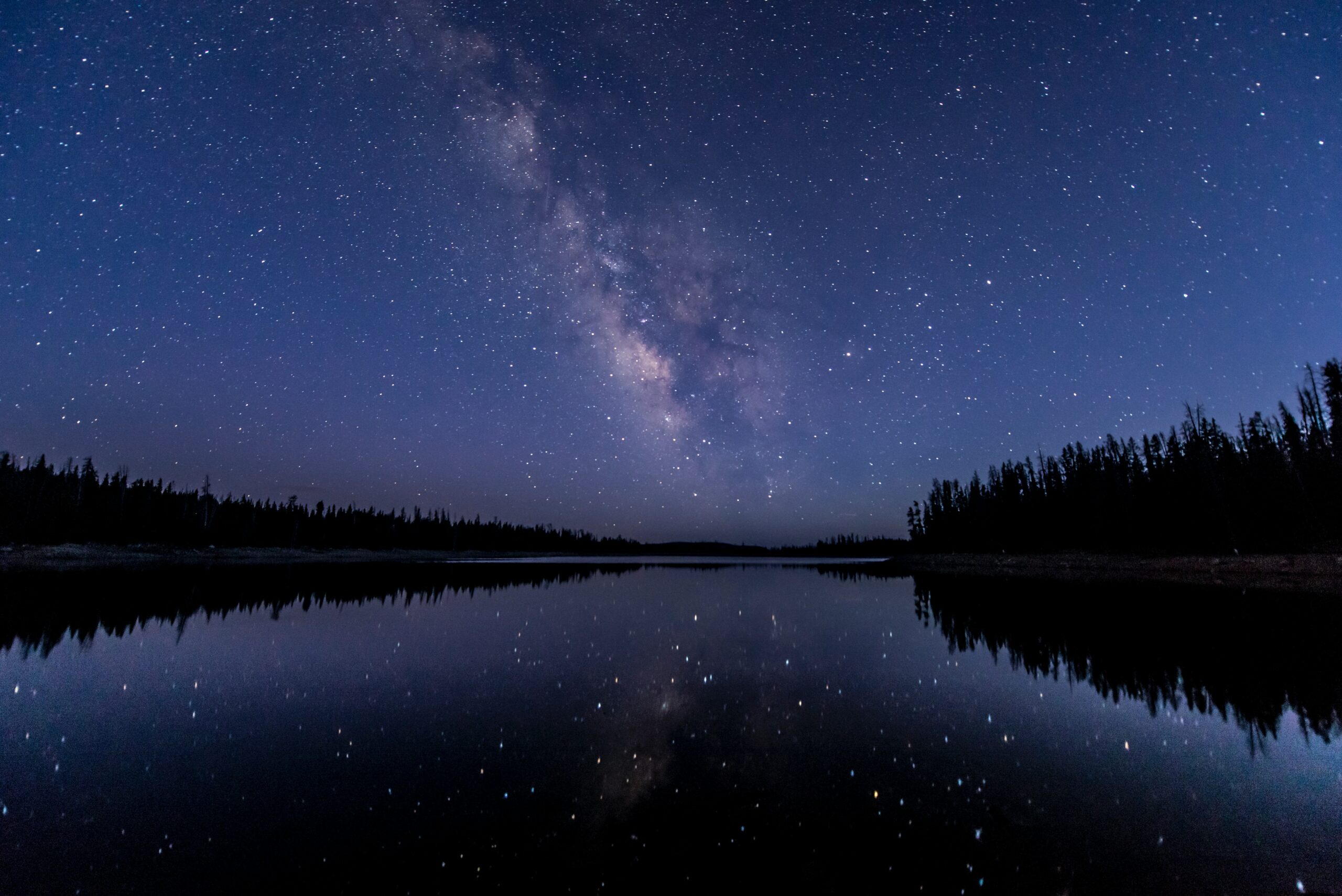 A night sky above a river and forest