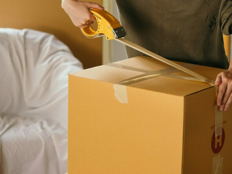 A woman taping a cardboard box shut