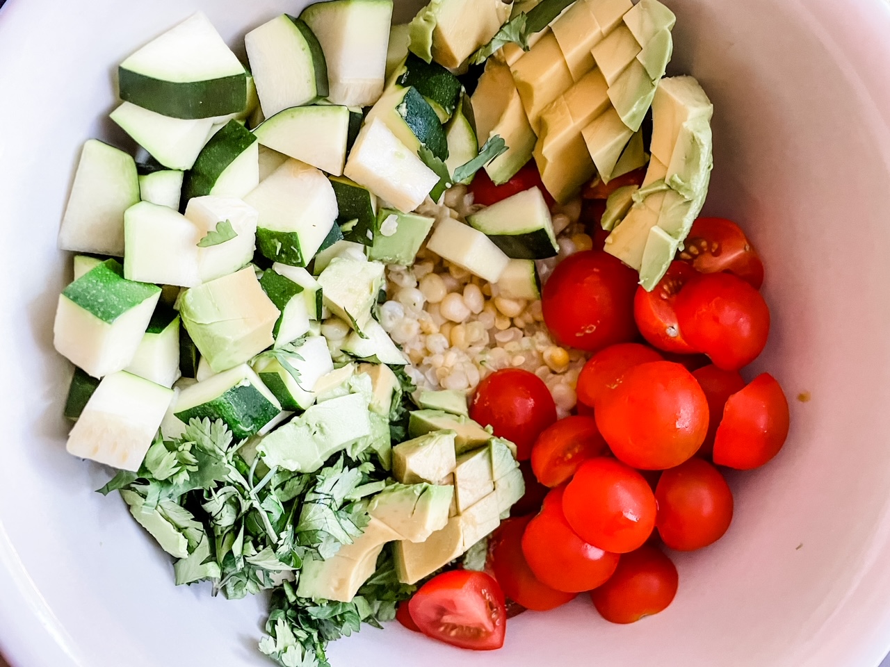 The Corn and Zucchini Salad with Avocado Dressing in a white bowl for serving