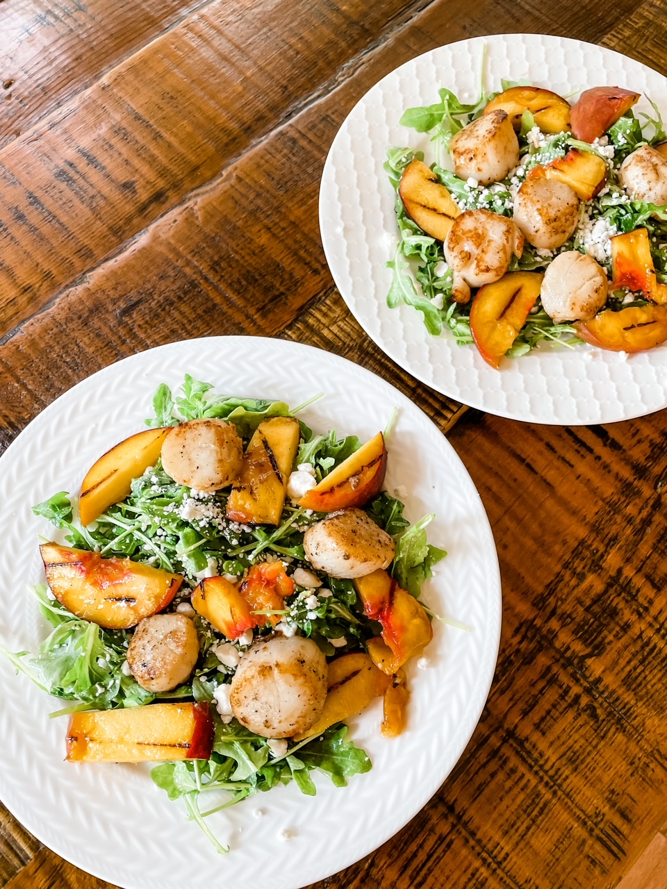 Two plates filled with the Arugula Salad with Scallops and Grilled Peaches