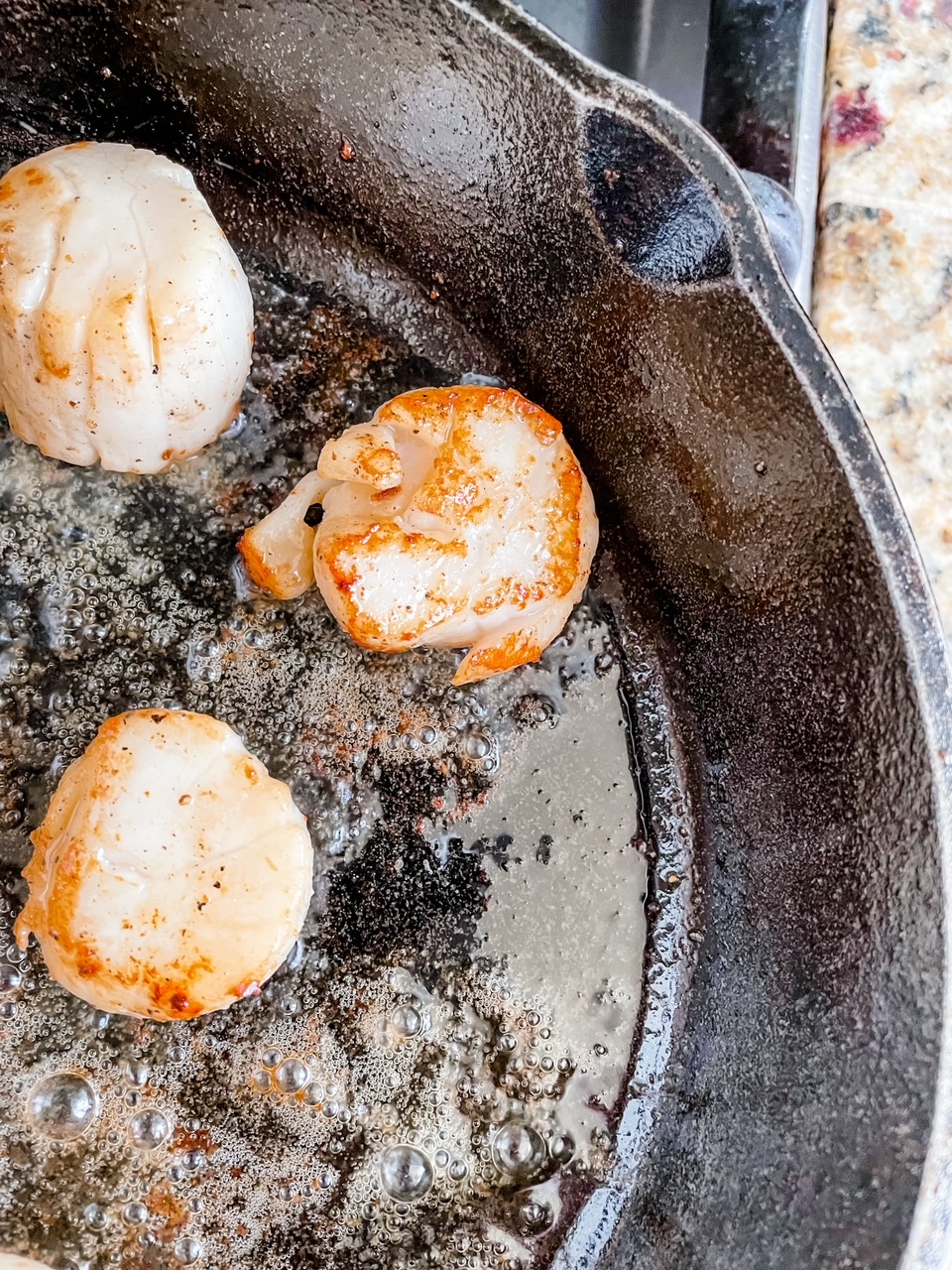 Three scallops in the cast-iron skillet