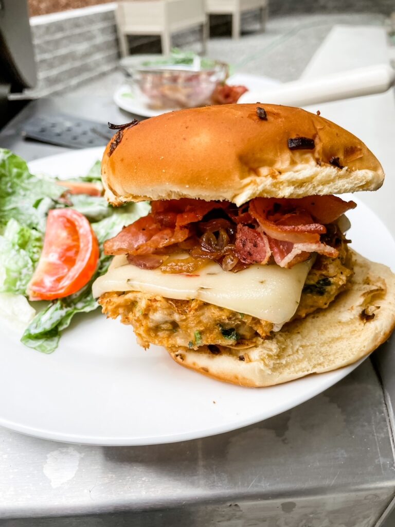 The Chicken Bacon Burgers on a plate, with a small salad next to it