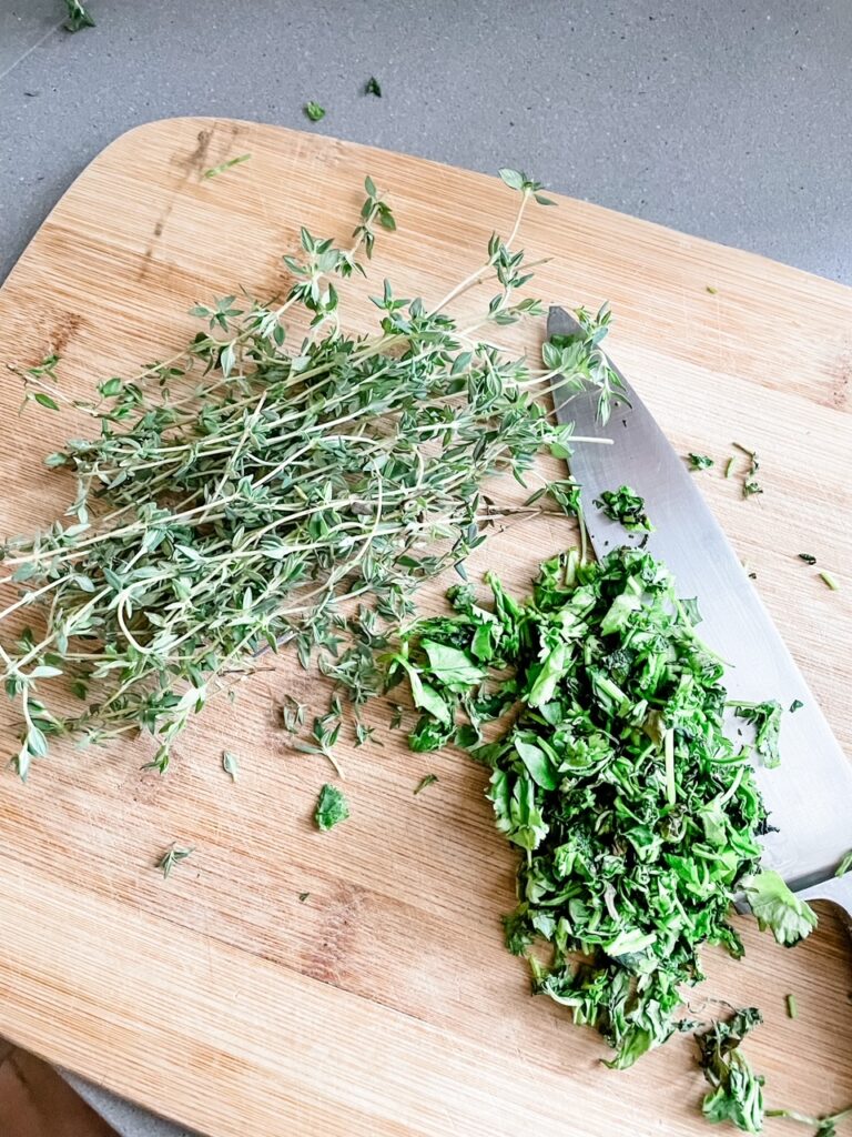 Thyme and cilantro being chopped on a cutting board