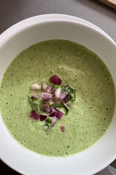 A bowl of the Cold Cucumber Soup garnished with chopped red onions