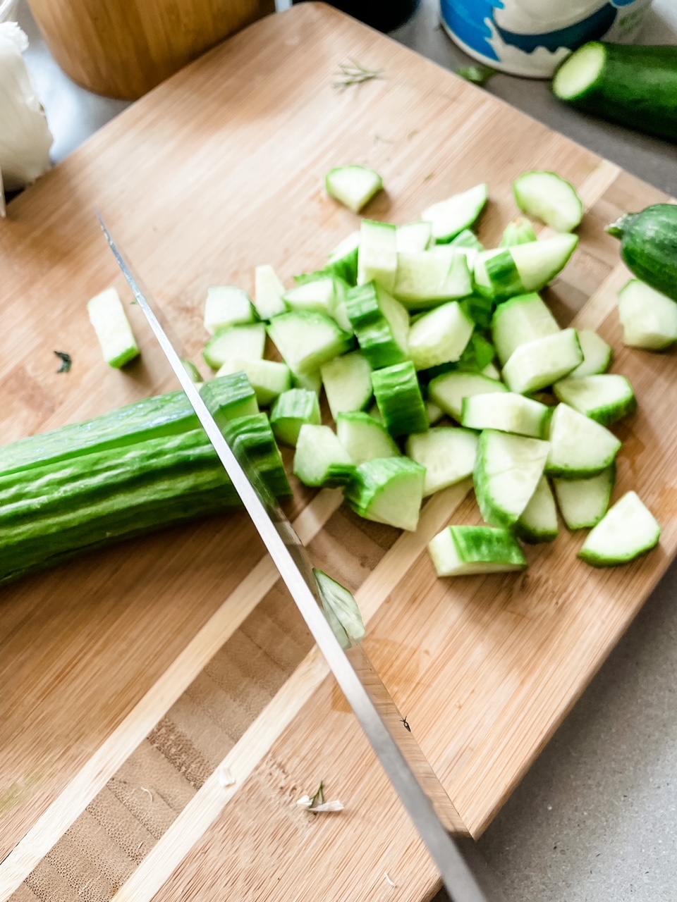 One of the english cucumbers being sliced up up on a wooden board