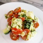 A serving of the Corn and Zucchini Salad with Avocado Dressing on a white plate