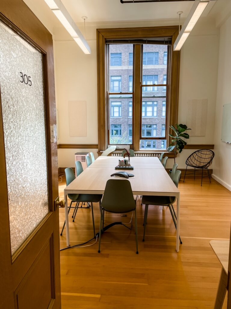 A conference room space with a long table and several chairs - a pro of the coworking space pros and cons