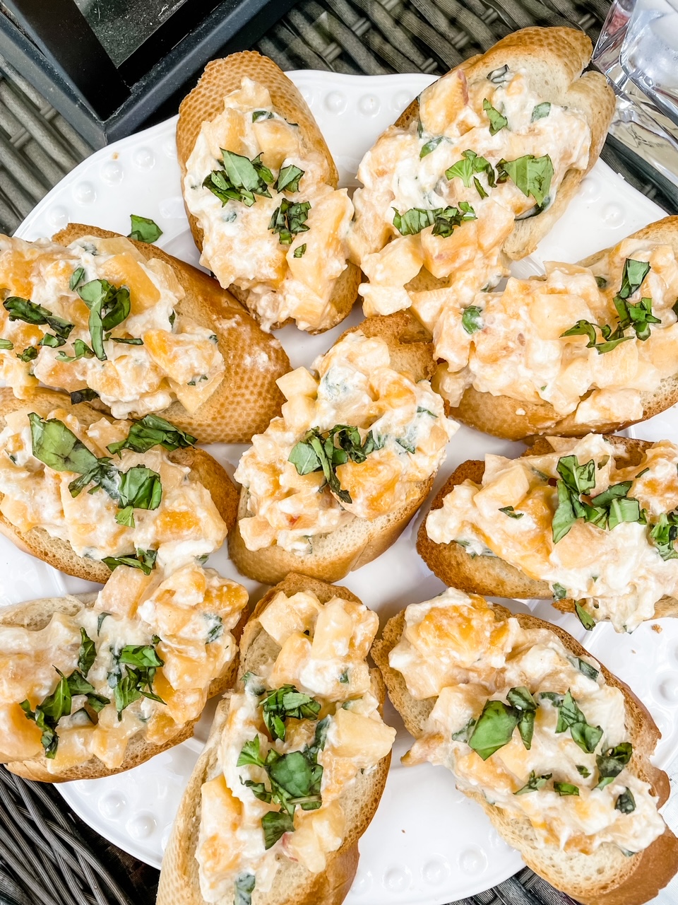 Slices of toast topped with the Fresh Peach and Burrata Bruschetta mixture and served together on a white plate