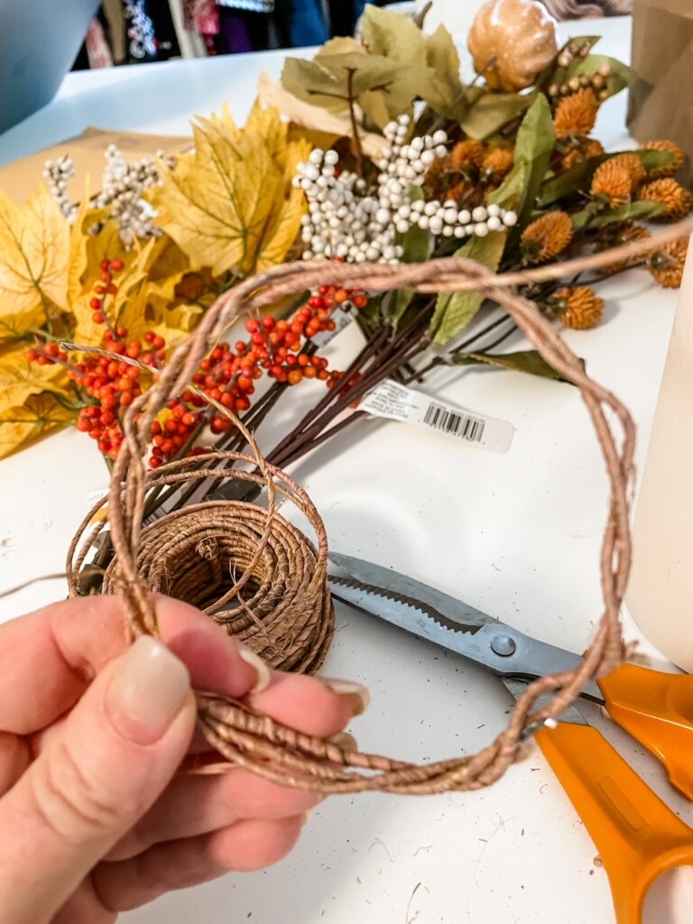 The leaves being attached to the hemp wire for the DIY Fall Candle Wreath