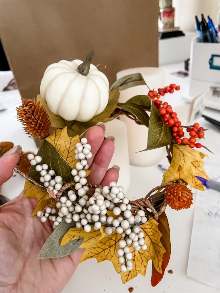 Mini pumpkins and fake berries being added to the DIY Fall Candle Wreaths