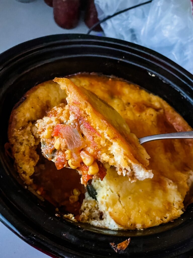 The Easy Slow Cooker Tamale Pie in a slow cooker, with a spoon digging in