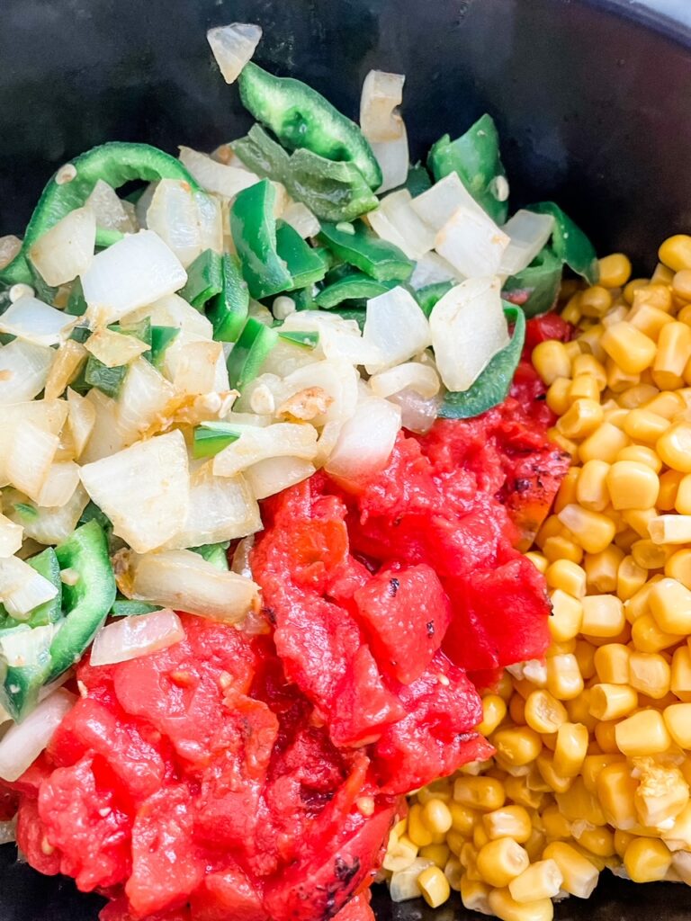 The onion, peppers, tomatoes, and corn in the slow cooker