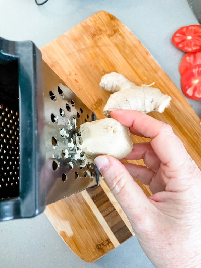 Marie grating the peeled ginger on a cutting board