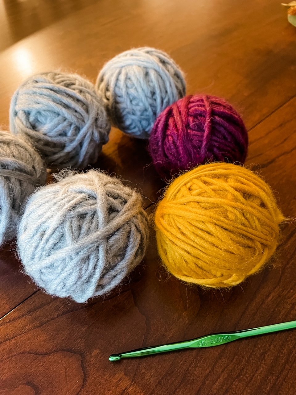 Six of the DIY Yarn Dryer Balls placed on a table with a crochet hook