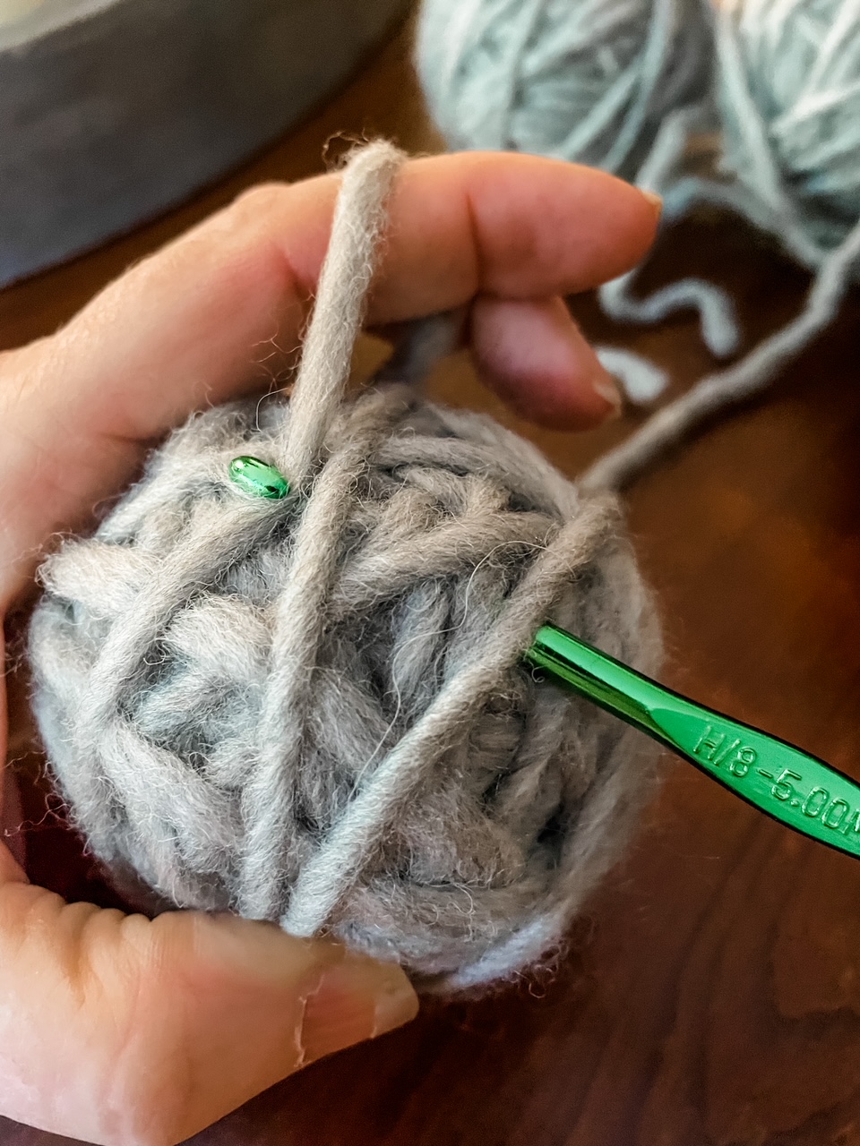 The ends of the wool yarn being woven into the ball with a crochet hook