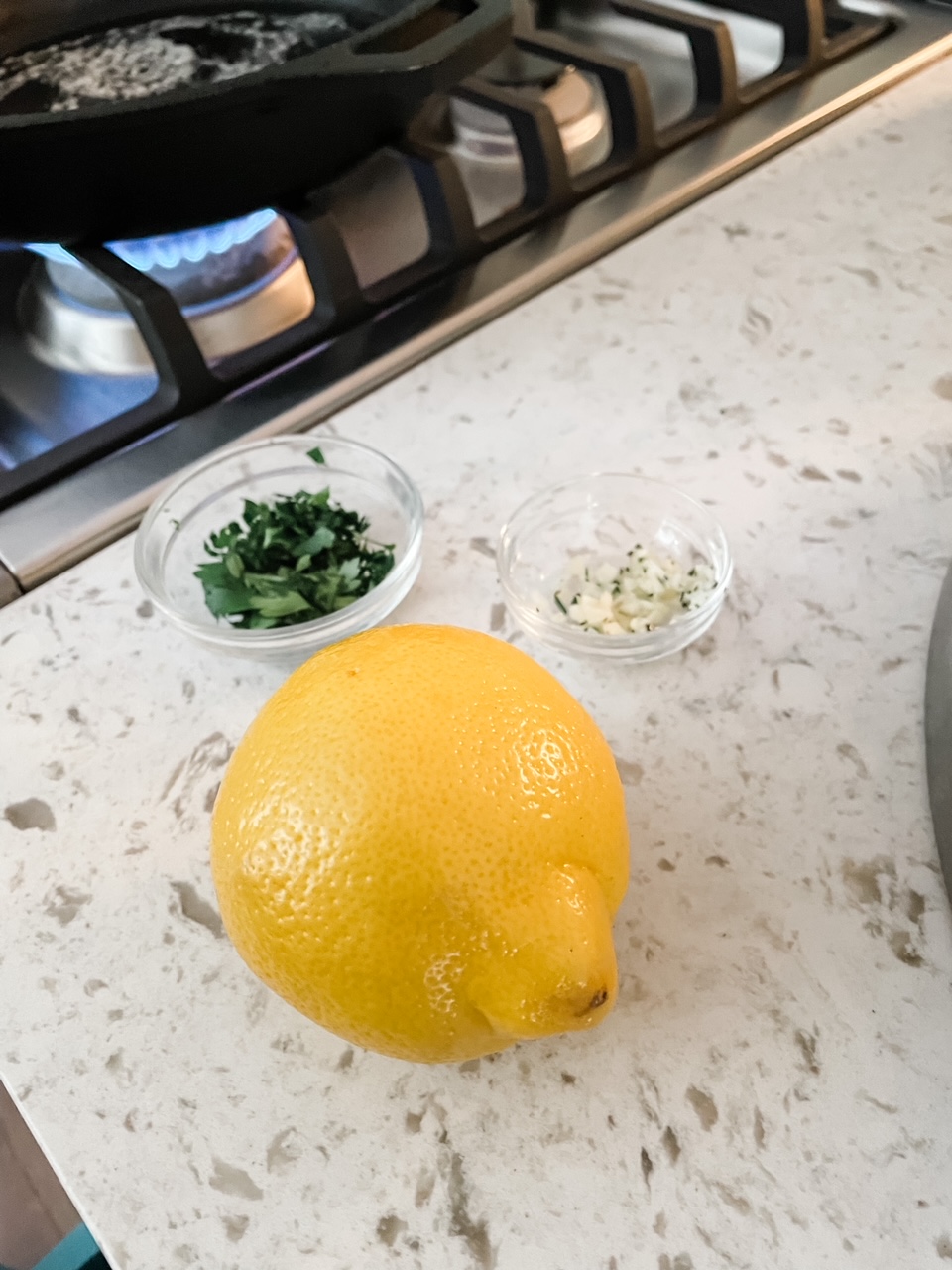 A lemon and two containers of parsley and garlic on a countertop