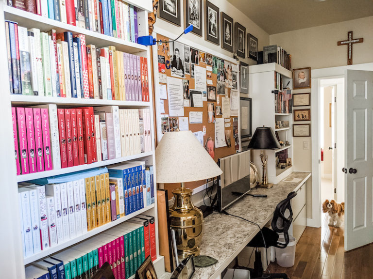 A small office space with bookshelves, a monitor, and posterboard