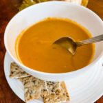 A bowl of the Vegan Crock Pot Pumpkin Soup with White Beans with a side of crackers