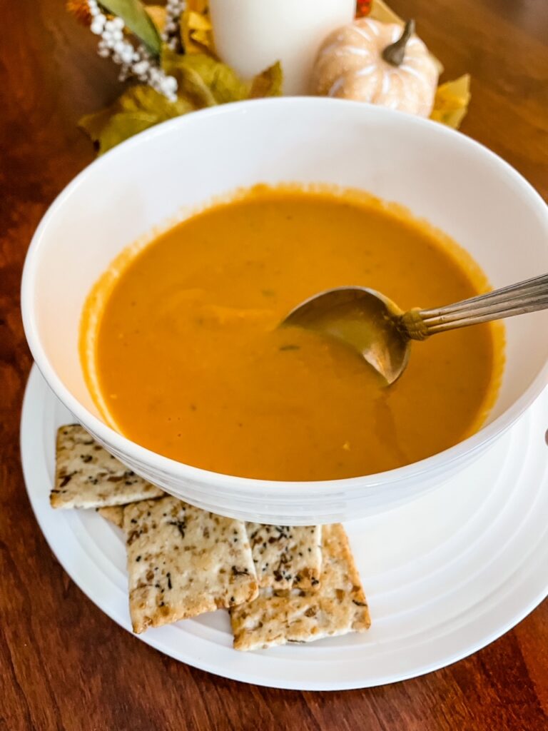 A bowl of the Vegan Crock Pot Pumpkin Soup with White Beans with a side of crackers