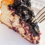 A slice of the Blueberry Greek Yogurt Cheesecake with a fork digging into it