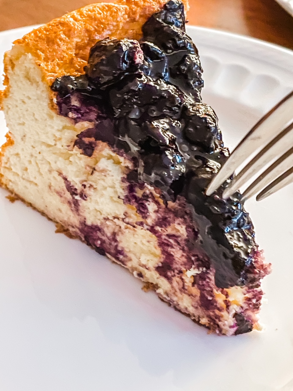 A slice of the Blueberry Greek Yogurt Cheesecake with a fork digging into it