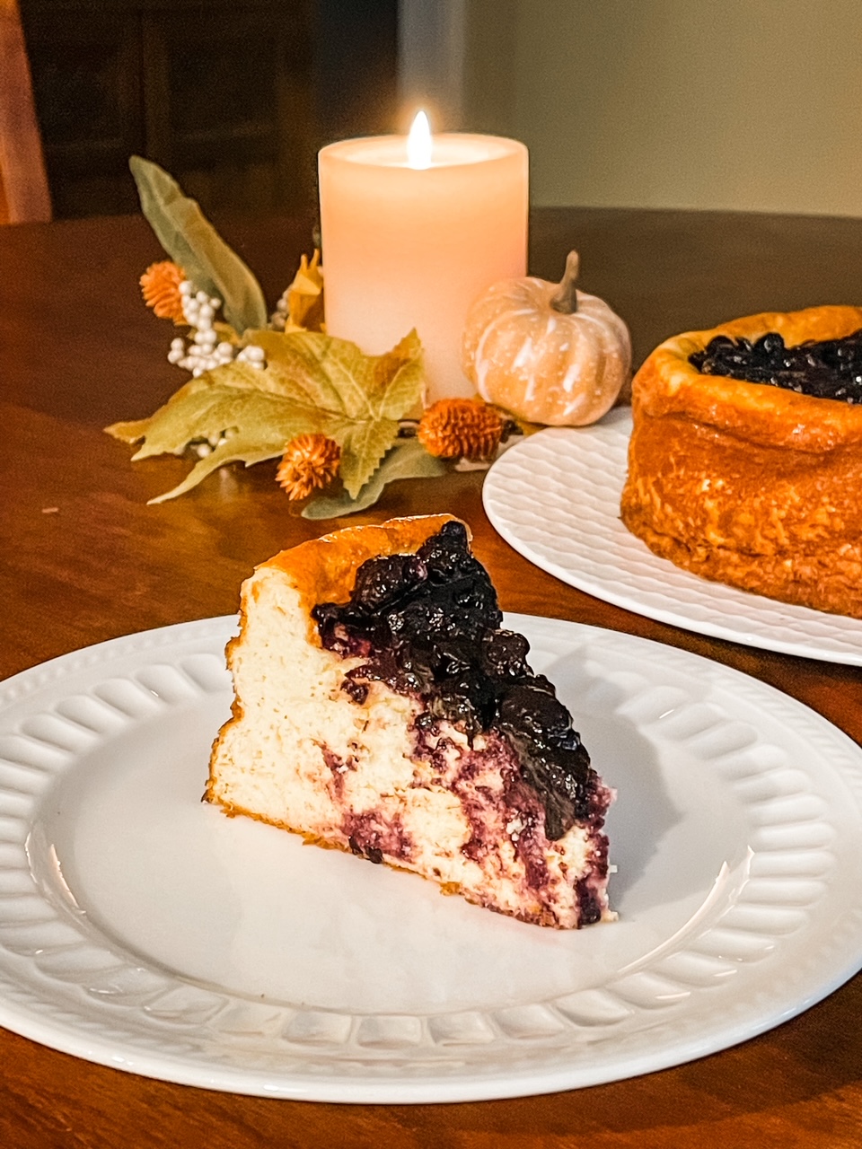 A slice of the Blueberry Greek Yogurt Cheesecake with the rest in the background