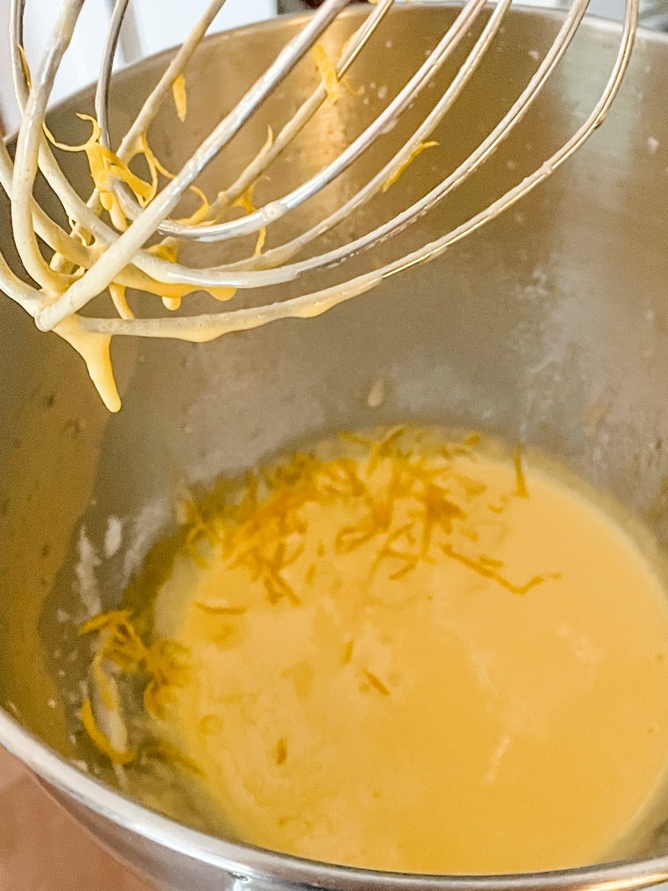 A whisk attachment with some of the batter dripping off