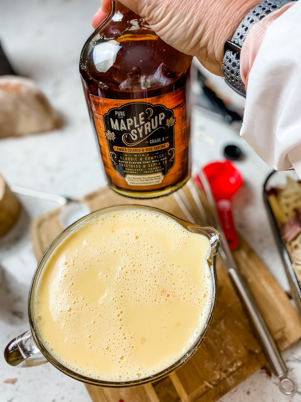 The egg, cream, and syrup custard with the bottle of maple syrup being held above