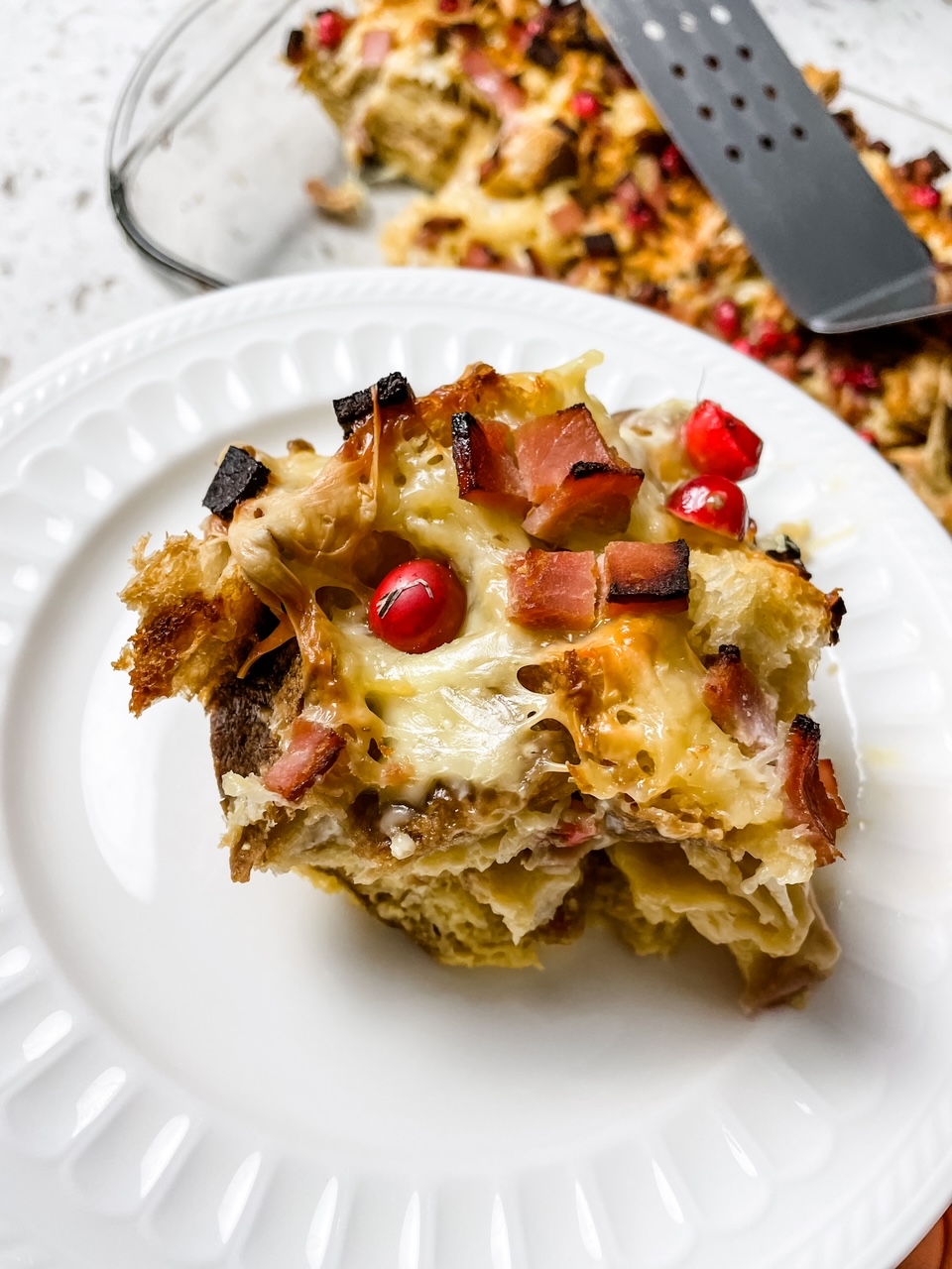A slice of the Cranberry, Ham and Swiss Cheese Breakfast Casserole, served on a white plate