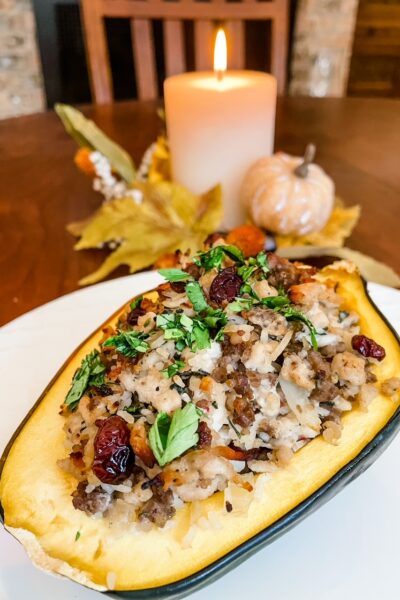 The finished Healthy Stuffed Baked Acorn Squash  on a white plate in front of a candle wreath