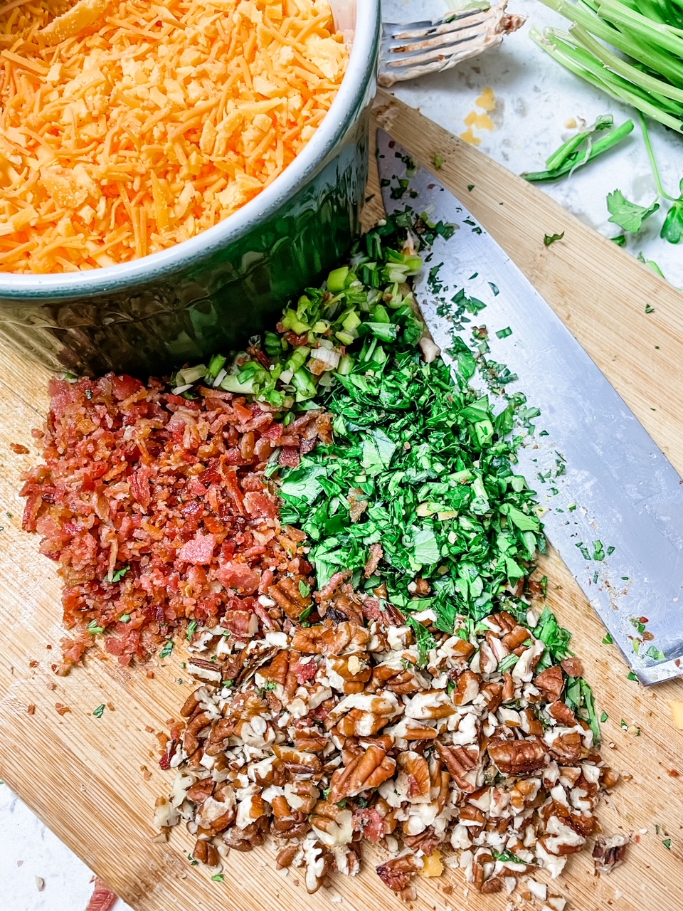 Some of the ingredients - bacon, pecans, and green onion - chopped up on a cutting board