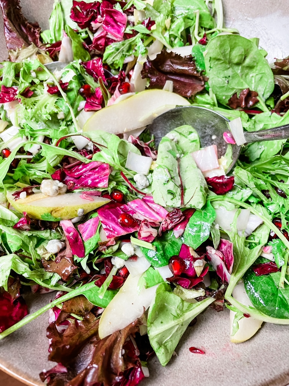 A partially consumed Pomegranate and Pear Salad with Citrus Dressing