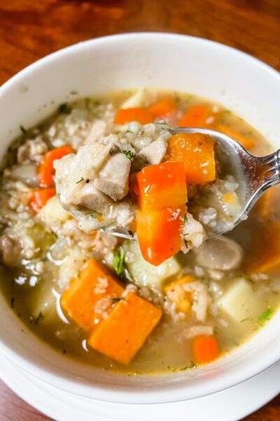 A bowl of Buckwheat Chicken Soup with Sweet Potato with a spoon