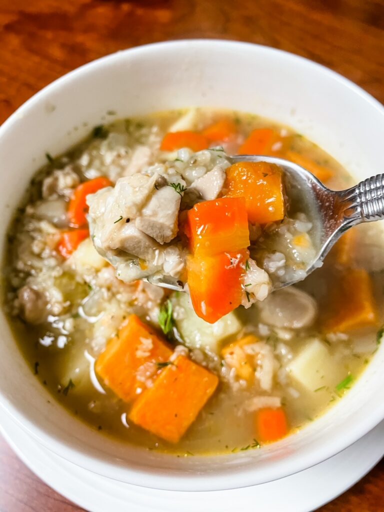 A bowl of Buckwheat Chicken Soup with Sweet Potato with a spoon