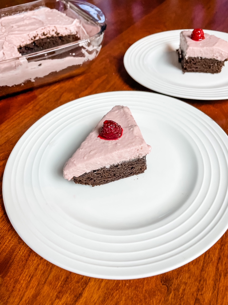 Two white plates with two slices of the Easy Raspberry Chiffon Brownie Cake