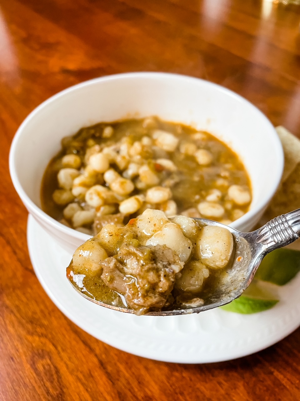A bowl of the Easy Pozole with Hatch Chiles with a spoon lifting up some