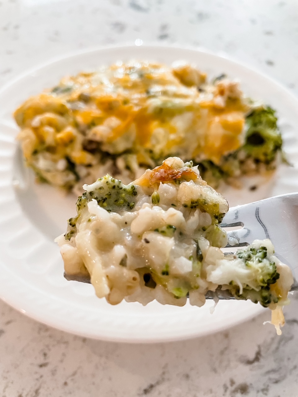 A fork lifting a bite of the Healthier Broccoli Rice Casserole with Chicken up